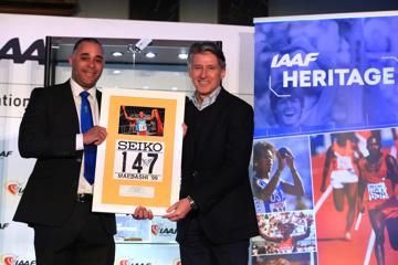 Jason Gardener presents IAAF President Sebastian Coe with Haile Gebrselassie's bib from the 1999 World Indoor Championships